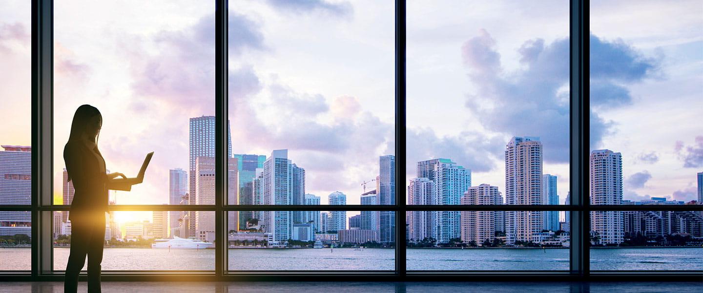 a person standing in front of a window looking out at a city